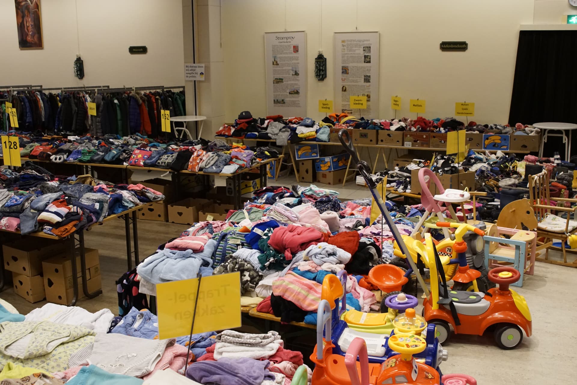 Tafels vol tweedehands kinderkleding en speelgoed op de Kinderbeurs in Stramproy